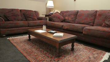 A living room with two sofas, a coffee table, and a patterned rug.