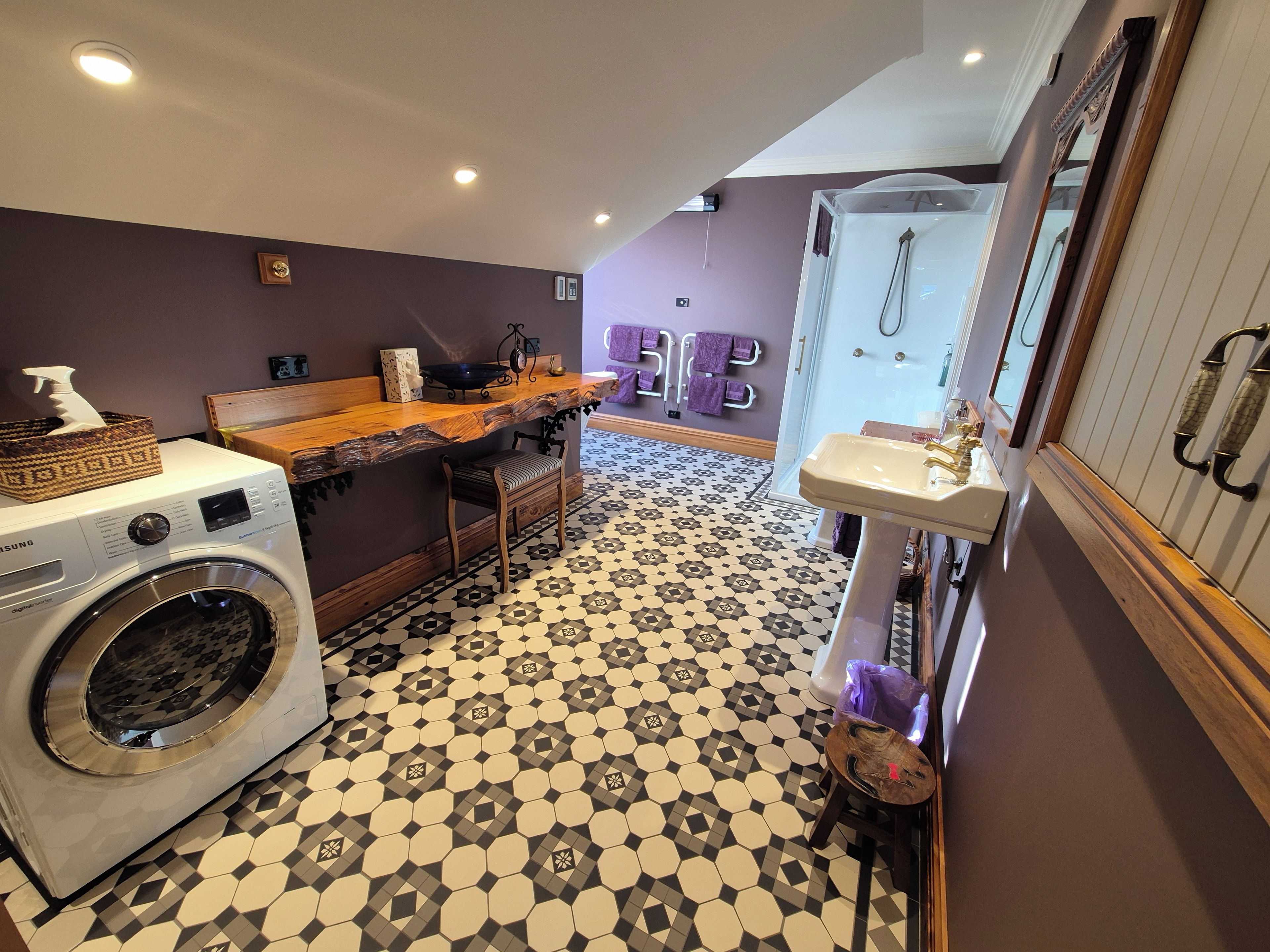 Zona de lavandería con lavadora, mostrador de madera y lavabo con espejo.