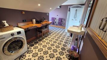 Zona de lavandería con lavadora, mostrador de madera y lavabo con espejo.