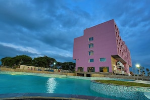 Ein modernes Gebäude mit Pool, umgeben von Bäumen und blauem Himmel.