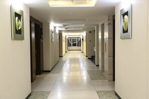 Ein Hotelkorridor mit Fliesenboden, Türen auf beiden Seiten und Wandbildern.