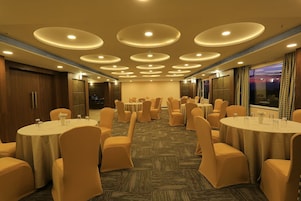 A conference room with multiple round tables, chairs, and a carpeted floor.