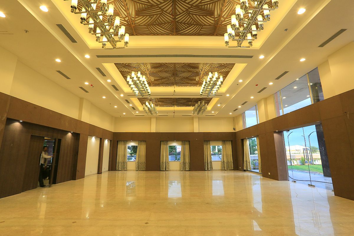 Un hall d’hôtel spacieux, doté d’un haut plafond, de grandes fenêtres et d’un lustre central.