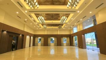 Un hall d’hôtel spacieux, doté d’un haut plafond, de grandes fenêtres et d’un lustre central.