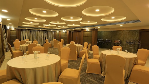 A banquet hall with round tables and chairs, recessed ceiling lighting, and a view of the city through large windows. - Nandankanan Hotel & Resorts  (Lohar Pipalya)