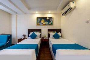 Ein Hotelzimmer mit zwei Betten, einem Nachttisch, einem Sessel und einem Bild an der Wand.