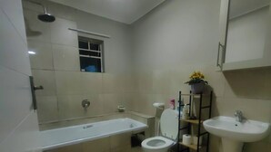 Casa de banho moderna com banheira, sanita, lavatório e uma pequena janela.