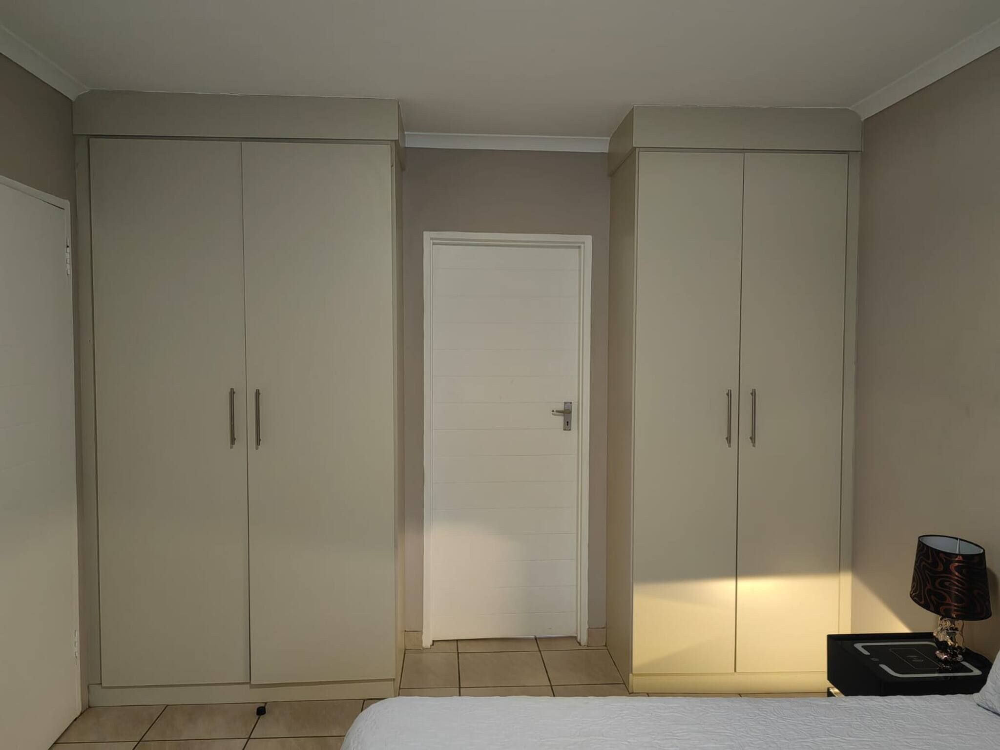 Un dormitorio con una cama, una mesita de noche, una lámpara y dos armarios.