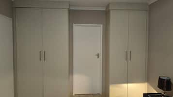 Un dormitorio con una cama, una mesita de noche, una lámpara y dos armarios.