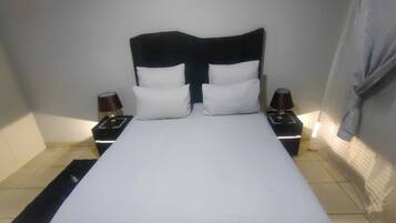 A standard hotel room with a bed, two bedside tables, and a nightstand with lamps.