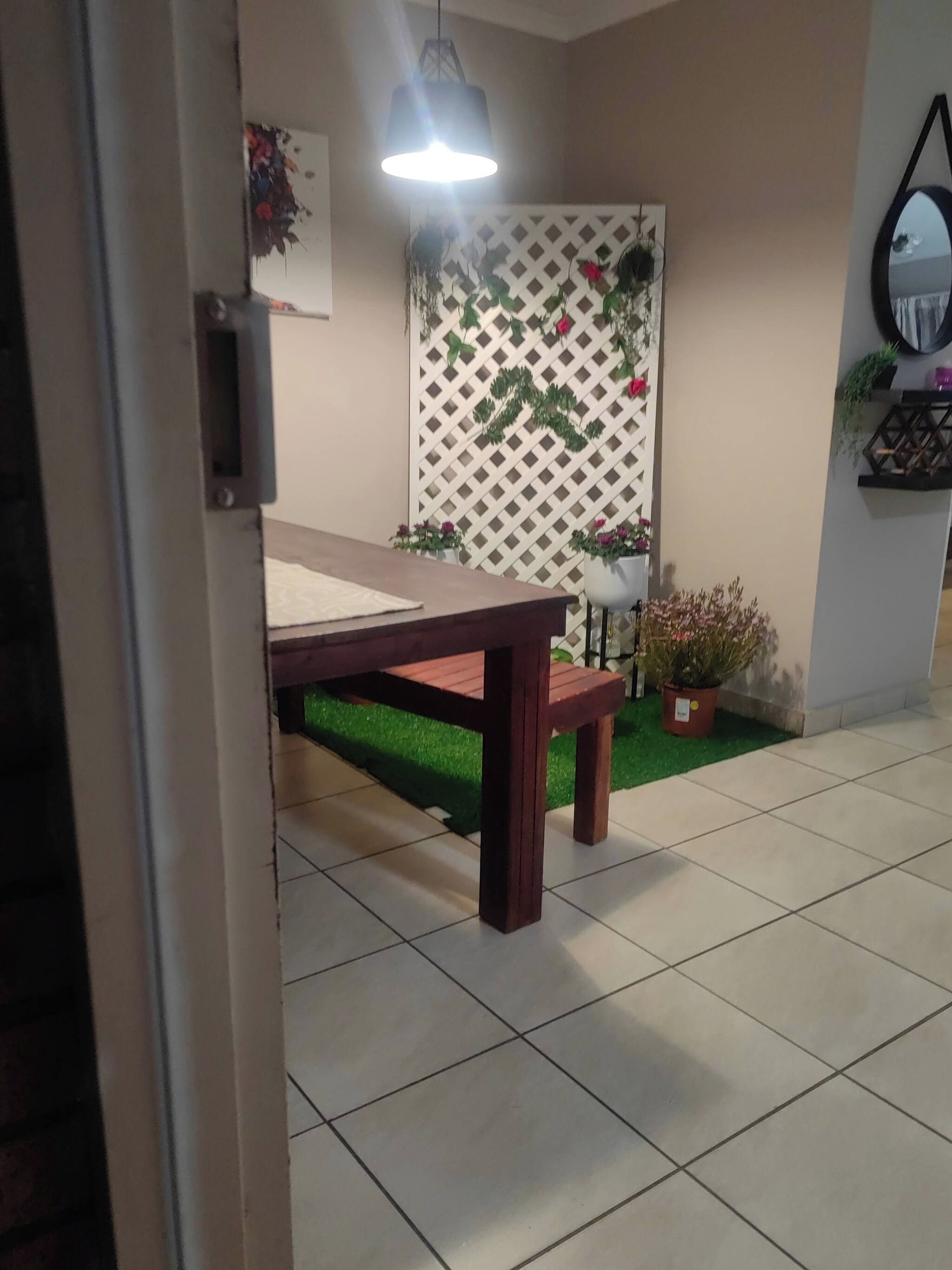Ein Zimmer mit Holztisch und Bank, einer Wand mit Pflanzenzierdekor und einer hängenden Lampe.