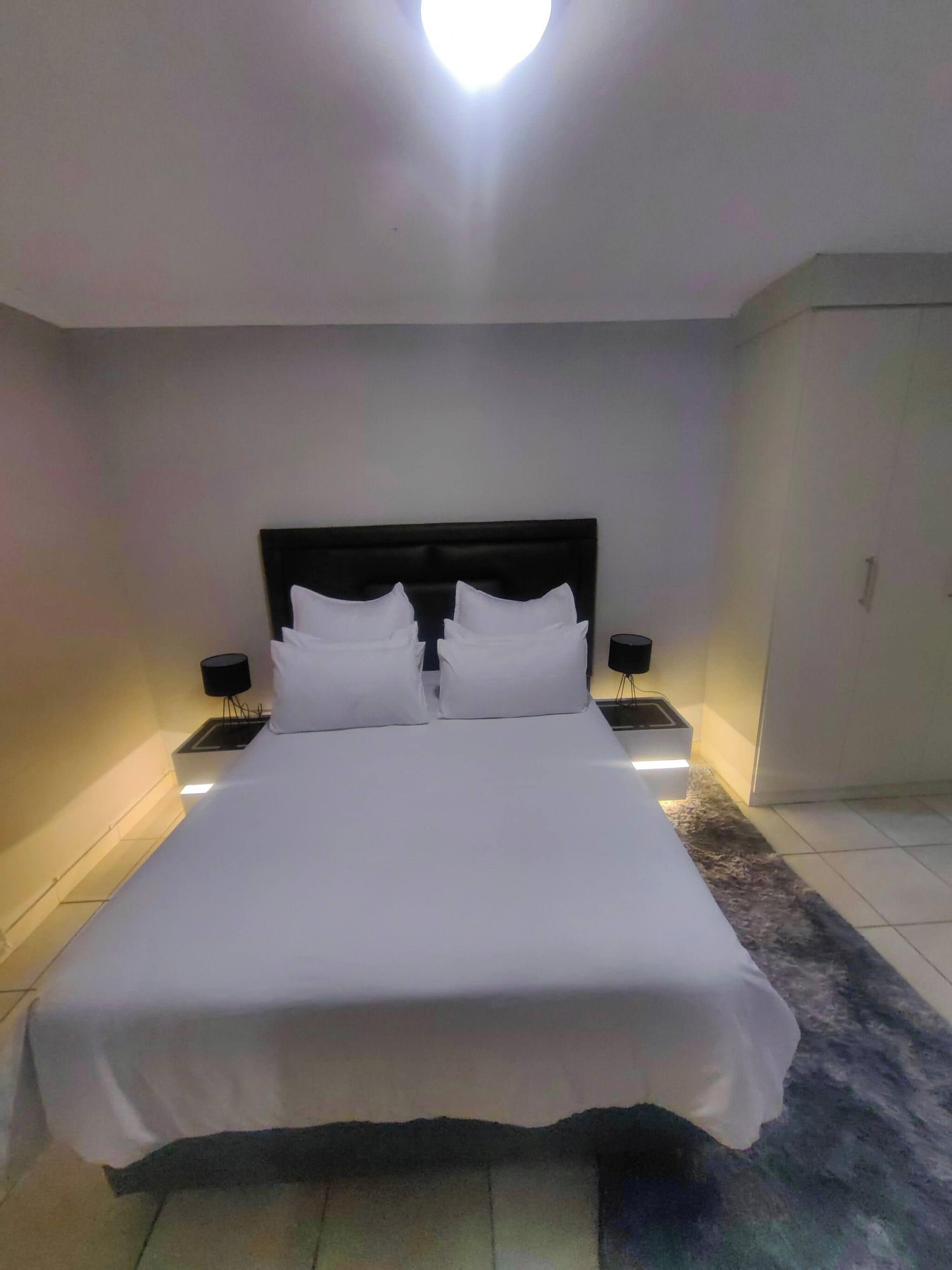 A hotel room with a large bed, two bedside tables, and a nightstand with a lamp.