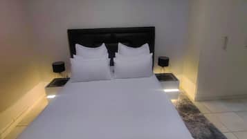 A hotel room with a large bed, two bedside tables, and a nightstand with a lamp.