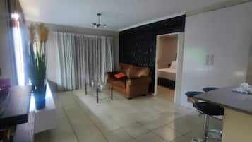 Una sala de estar moderna con un sofá, un comedor con mesa y sillas, y una zona de cocina con armarios.