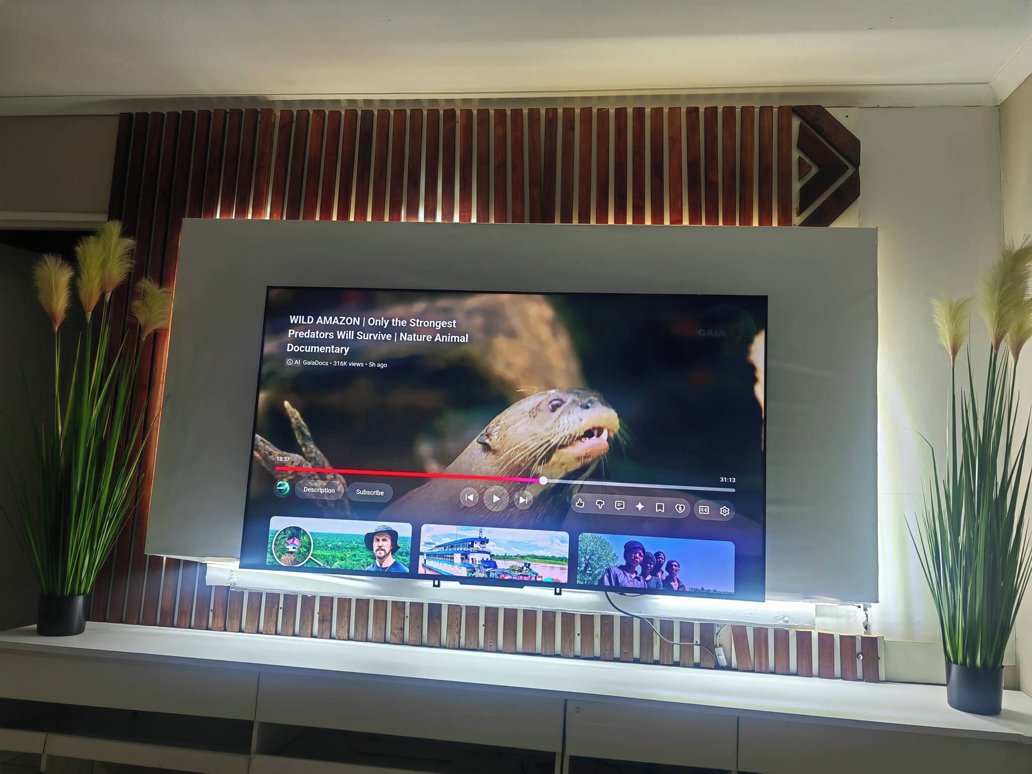 Un televisor de pantalla plana montado en la pared con un diseño de panel de madera encima.