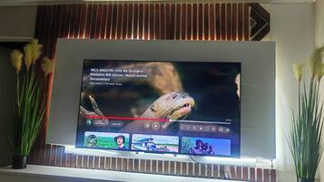 Un televisor de pantalla plana montado en la pared con un diseño de panel de madera encima.