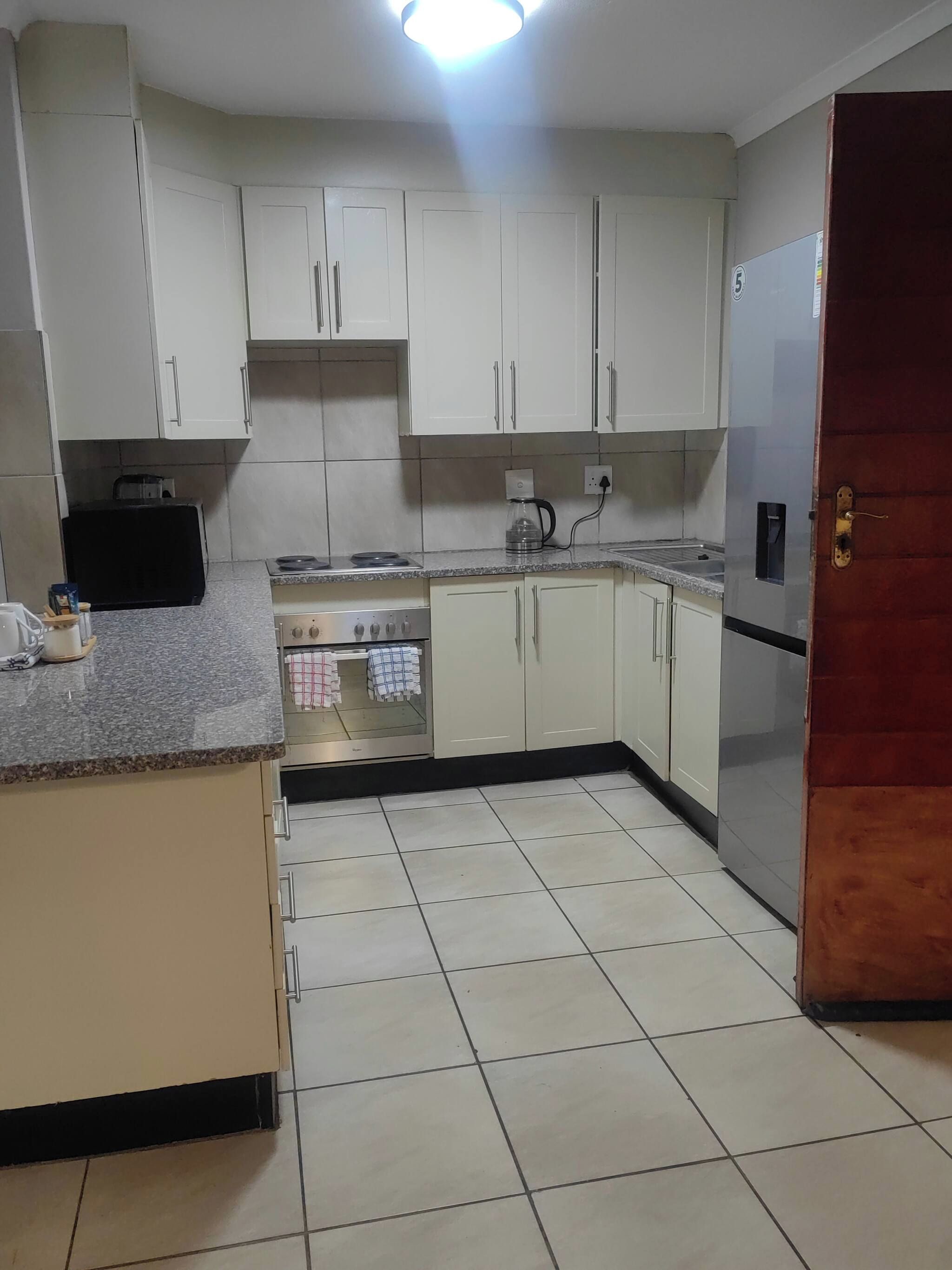 A kitchen with white cabinets, a stove, a sink, and a refrigerator.