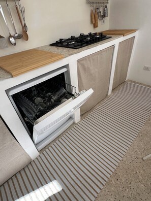 A compact kitchen with a built-in dishwasher, a gas stove, and a wooden countertop. - Casa Caprifoglio Noto two terraces (Noto)