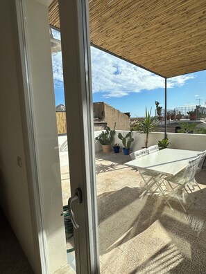 An outdoor patio with a table and chairs, potted plants, and a view of the sky and buildings. - Casa Caprifoglio Noto two terraces (Noto)