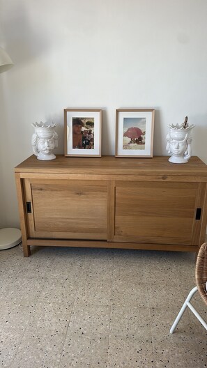 A wooden cabinet with two framed photographs and decorative vases on top. - Casa Caprifoglio Noto two terraces (Noto)