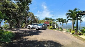 Una carretera con dos coches aparcados, un cartel de restaurante y vistas del paisaje.