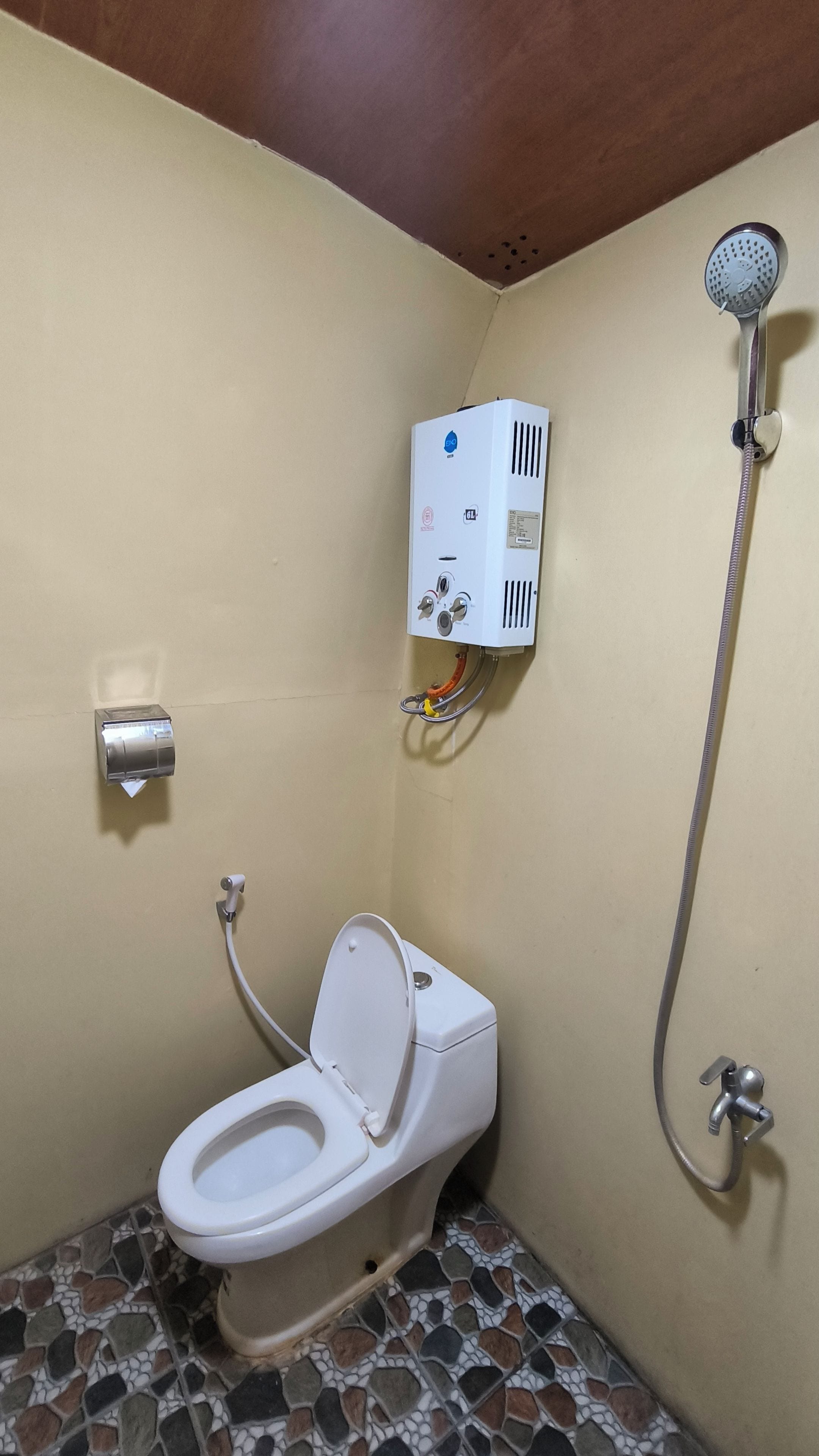 Un baño con inodoro, ducha y calentador de agua.