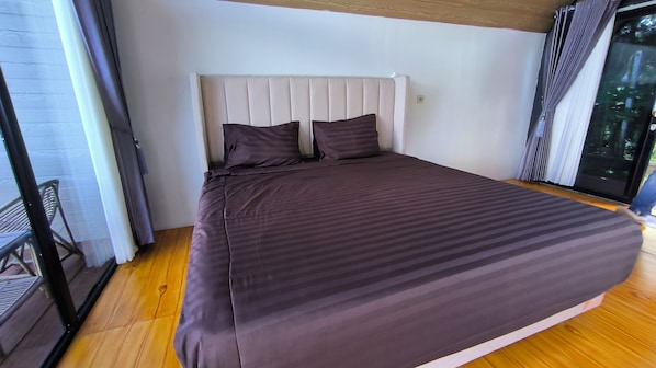 A bedroom with a bed, a headboard, and a view through a glass door.