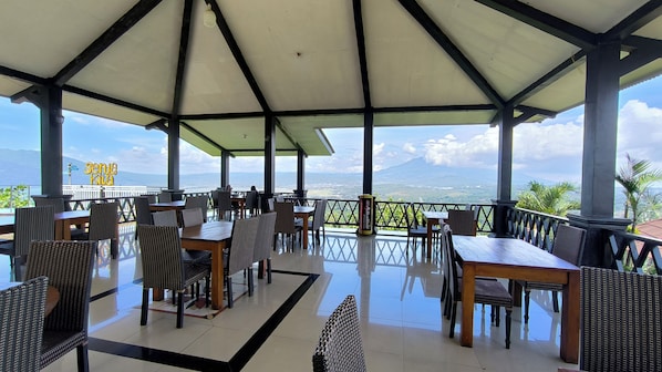 Un espace de restauration en plein air avec des tables et des chaises, un plancher en verre et une vue sur une chaîne de montagnes.