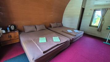 Una habitación con dos camas, un armario de madera, una tetera y una ventana con cortinas.