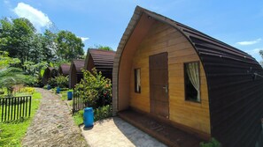 A row of wooden cabins with a stone pathway leading to them. - Senja Kita Glamping (Salatiga)
