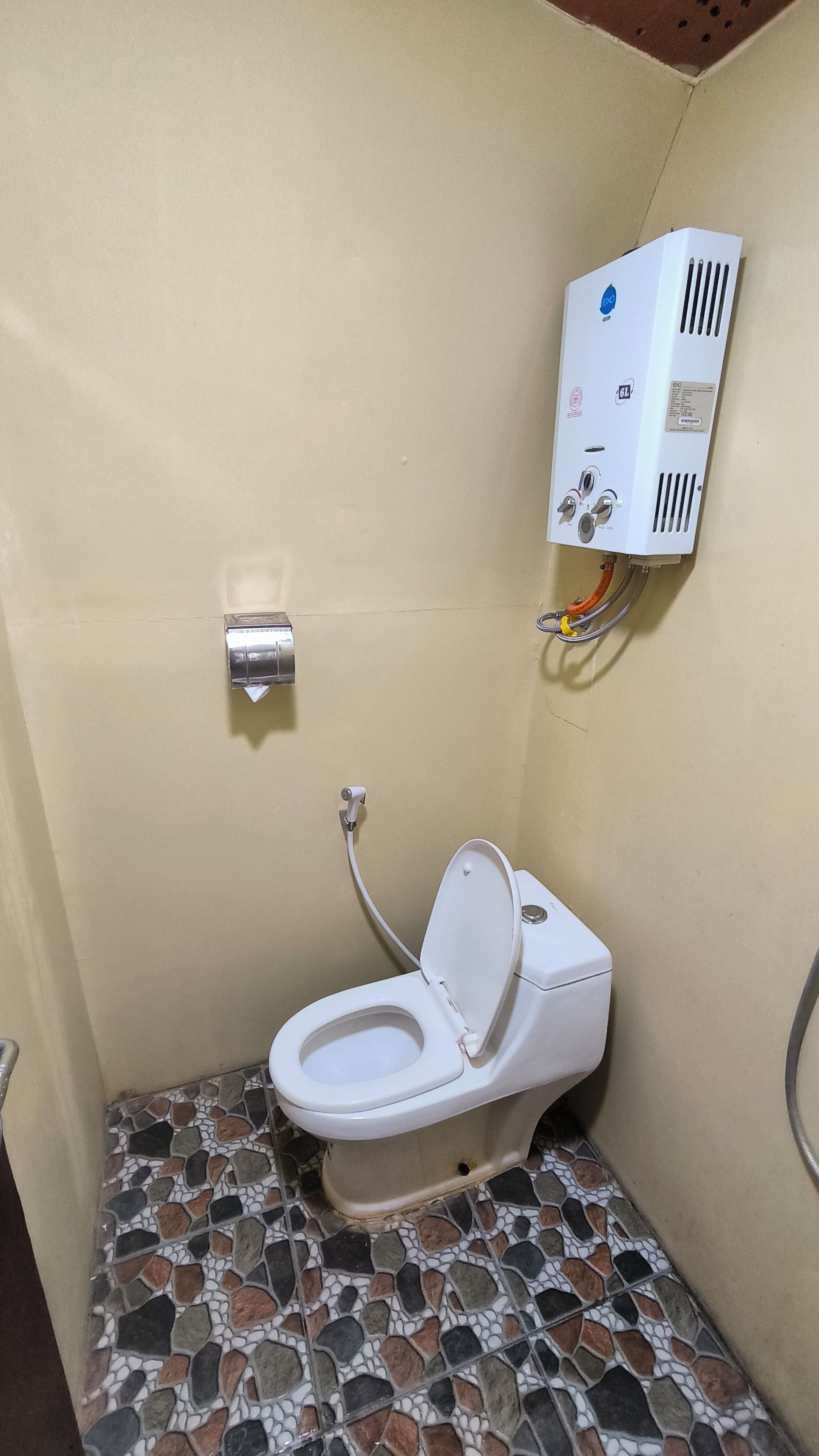 A small bathroom with a toilet, a water heater, and a tiled floor.