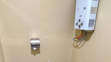 A small bathroom with a toilet, a water heater, and a tiled floor.