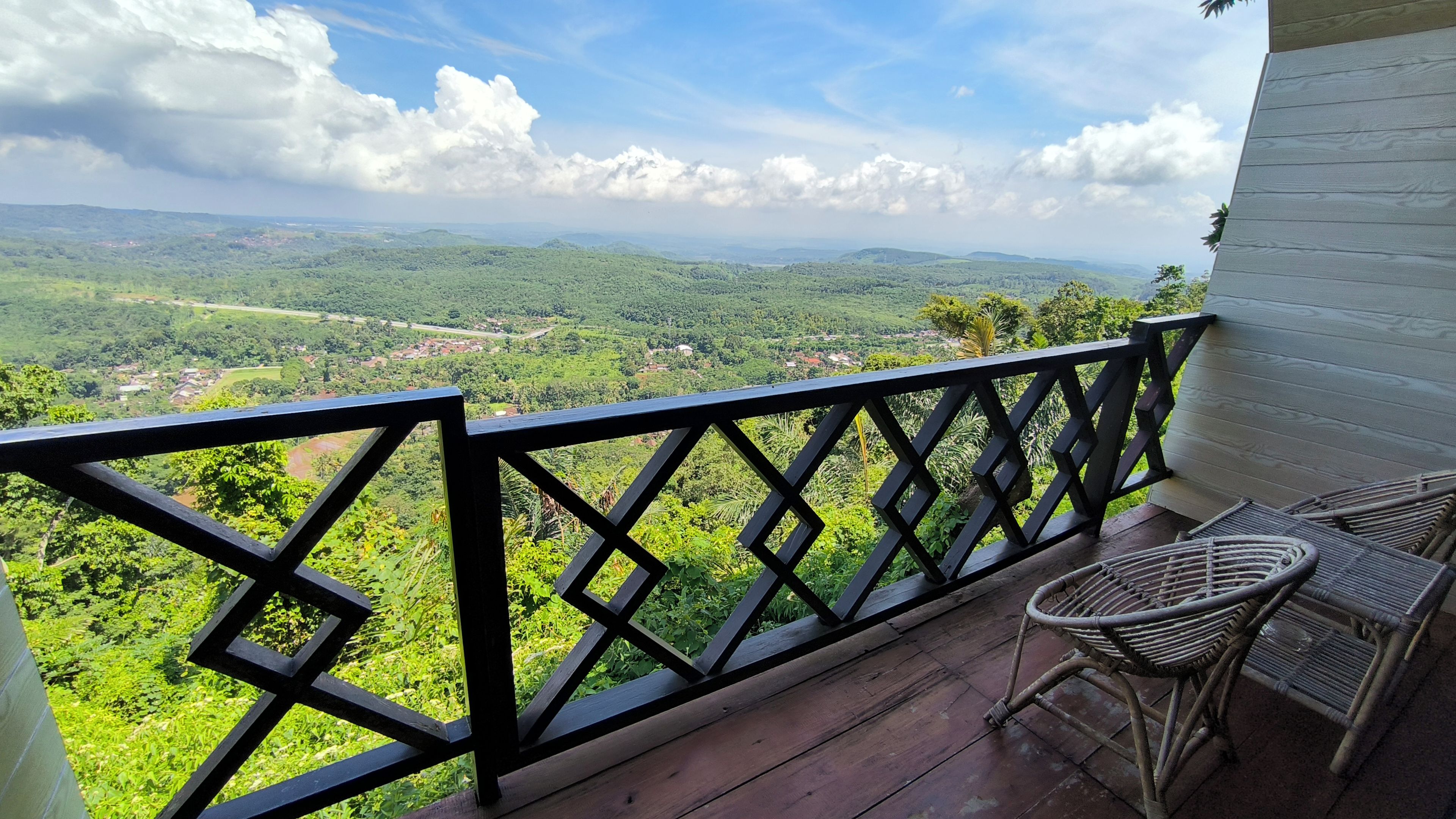 Un balcon donnant sur un paysage verdoyant et sur des collines lointaines.