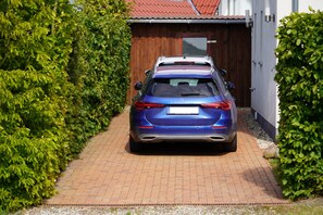 Ein blaues Auto auf einem gepflasterten Auffahrt, die zu einem Holztor führt.