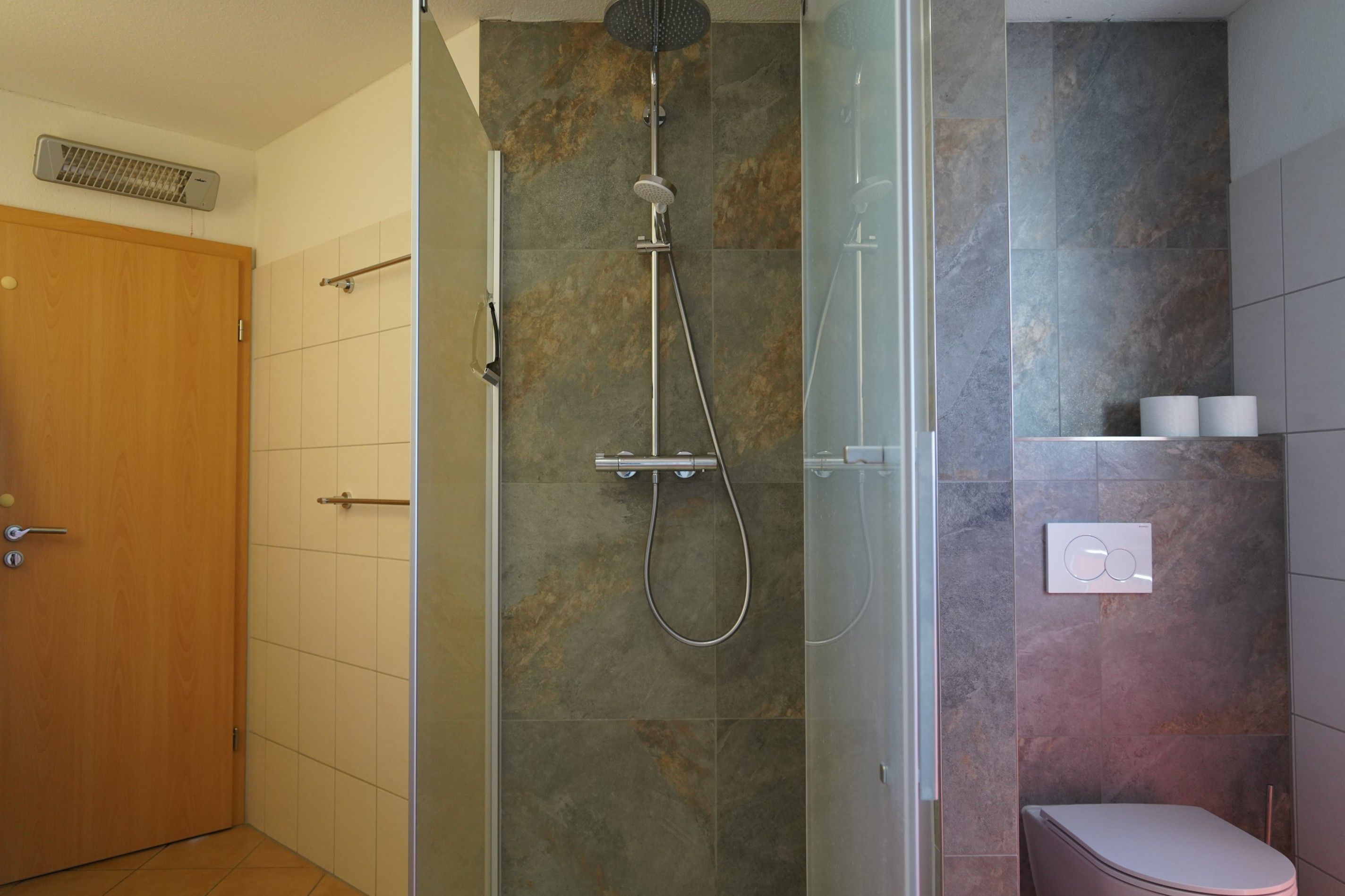 Ein Badezimmer mit Dusche, Toilette und Handtuchhalter.