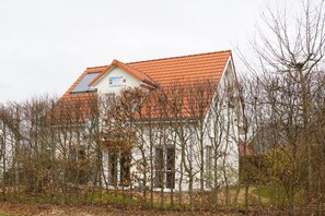 A two-story building with a red-tiled roof, surrounded by leafless trees.