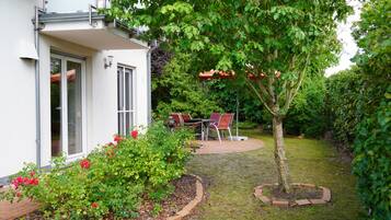 A residential garden with a patio, a dining table, and chairs.