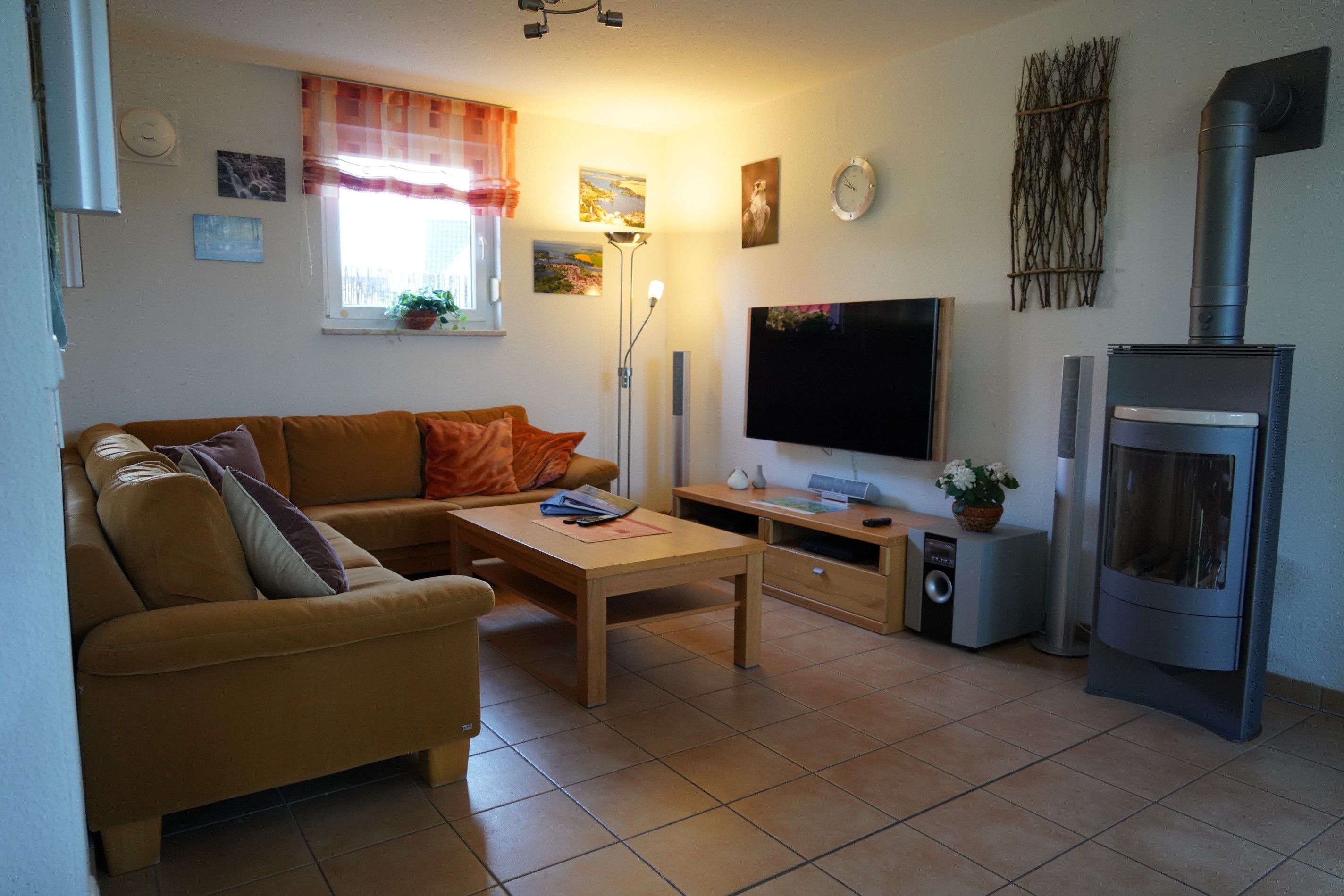 Ein Wohnzimmer mit einer Couch, einem Couchtisch, einem Flachbildfernseher, einem Kamin und einem Fenster mit Vorhängen.