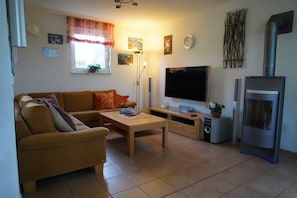 A living room with a sofa, a coffee table, a flat-screen TV, a fireplace, and a window with curtains.