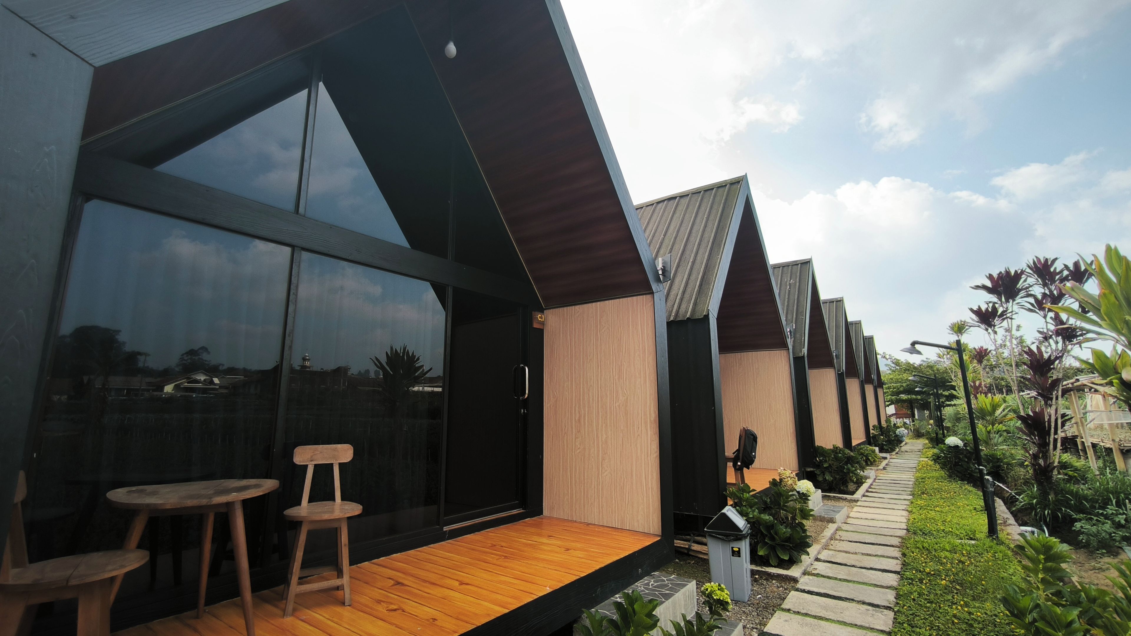 A modern building with large windows, a wooden deck, and a garden pathway.