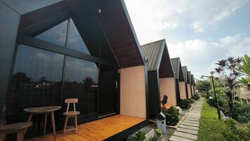 A modern building with large windows, a wooden deck, and a garden pathway.
