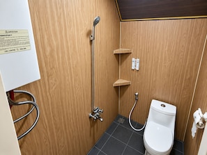 Une petite salle de bain équipée d’une douche, de toilettes et d’un panneau indiquant la présence d’un centre d’appels.