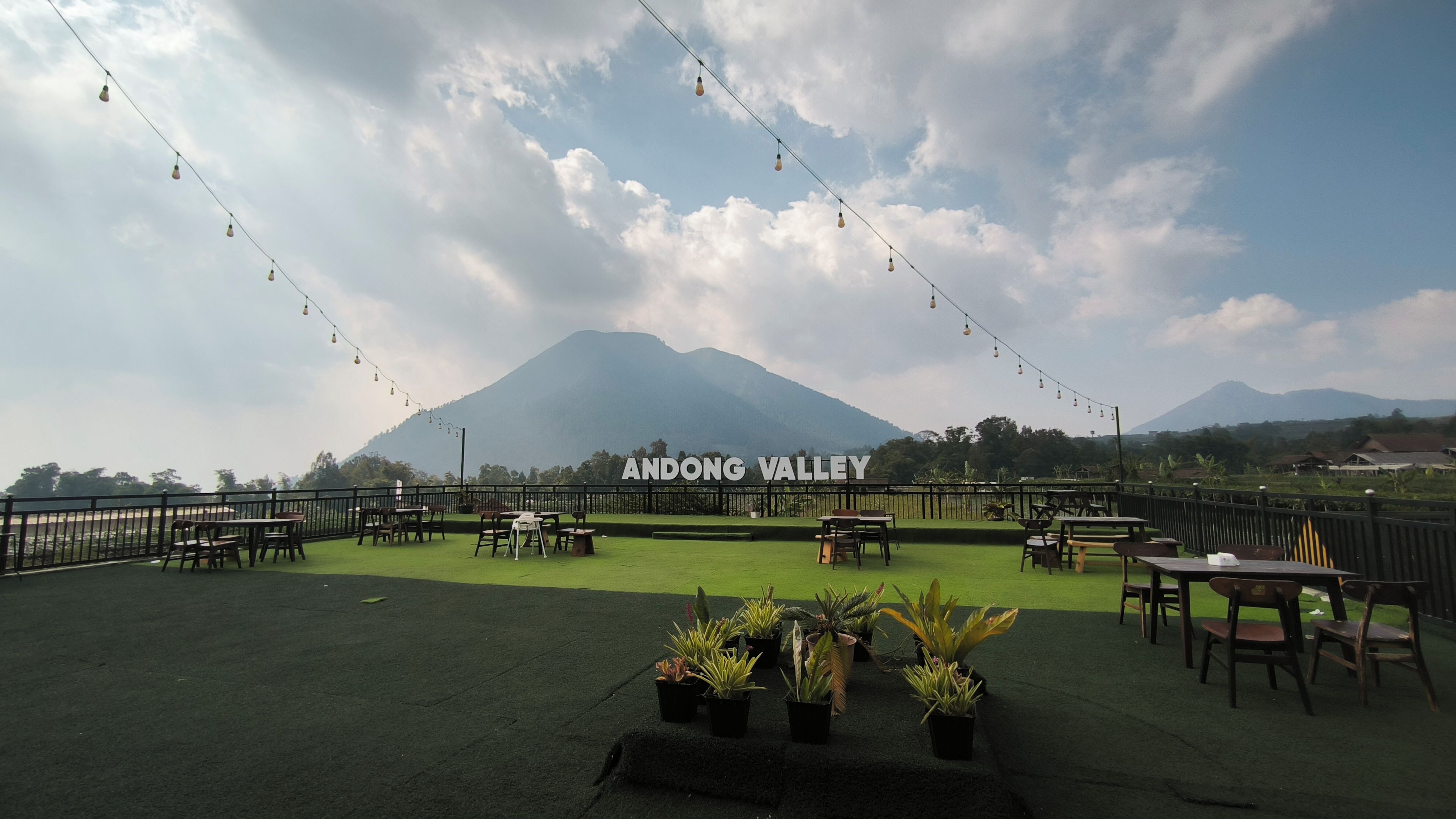 An outdoor seating area with tables and chairs, a sign reading 'ANDONG VALLEY', and a mountain in the background.