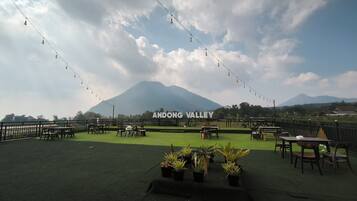 An outdoor seating area with tables and chairs, a sign reading 'ANDONG VALLEY', and a mountain in the background.