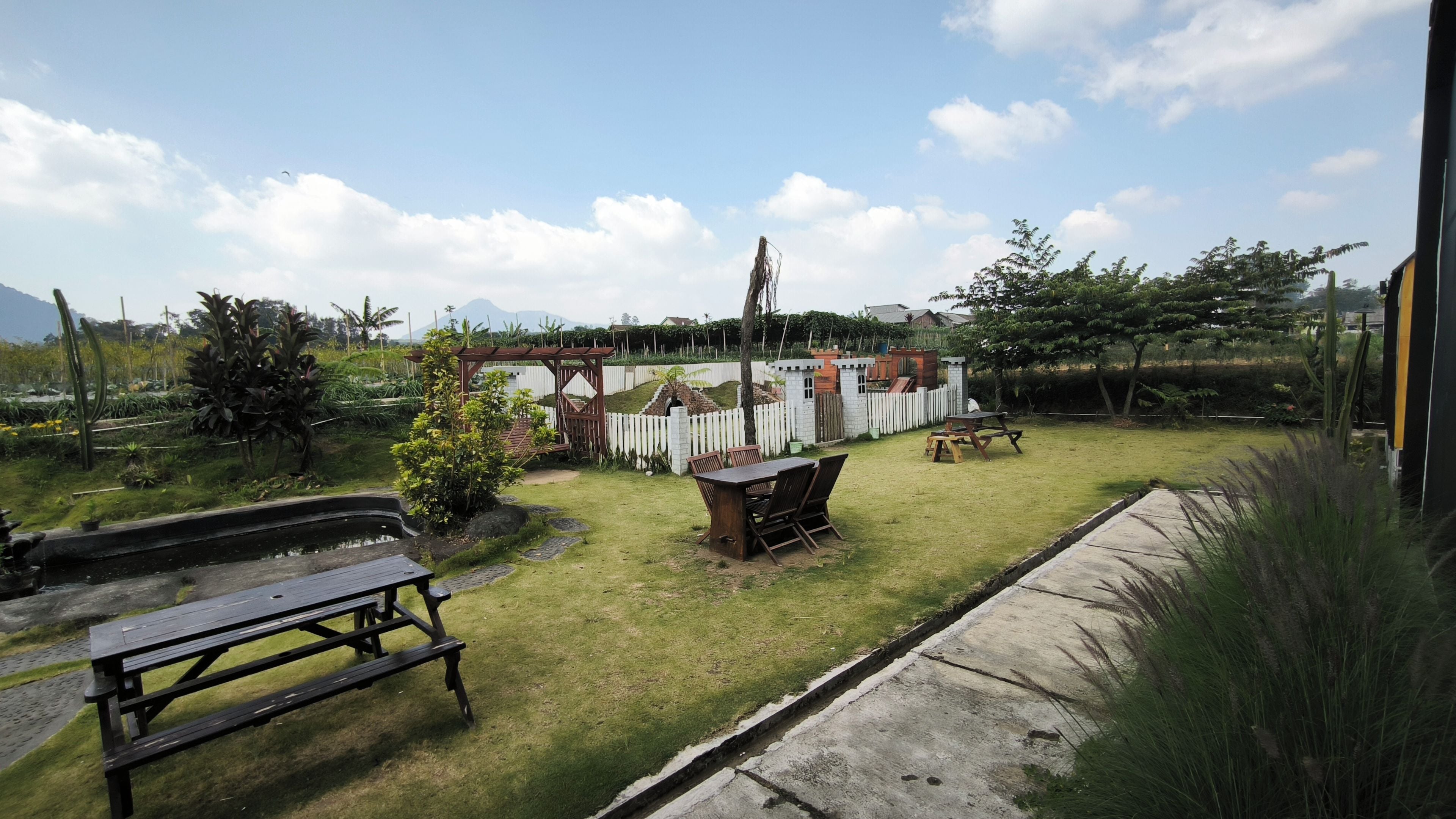 A backyard with a picnic table, a small garden, and a white picket fence.