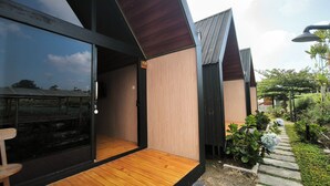 Uma casa moderna com deck de madeira, porta de vidro e um jardim com plantas e um caminho.