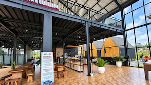 Amplo espaço interno com piso de madeira, varanda e janelas grandes que oferecem vista para o exterior.
