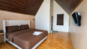A modern bedroom with a large bed, wooden flooring, a flat-screen TV mounted on the wall, and a wooden ceiling.