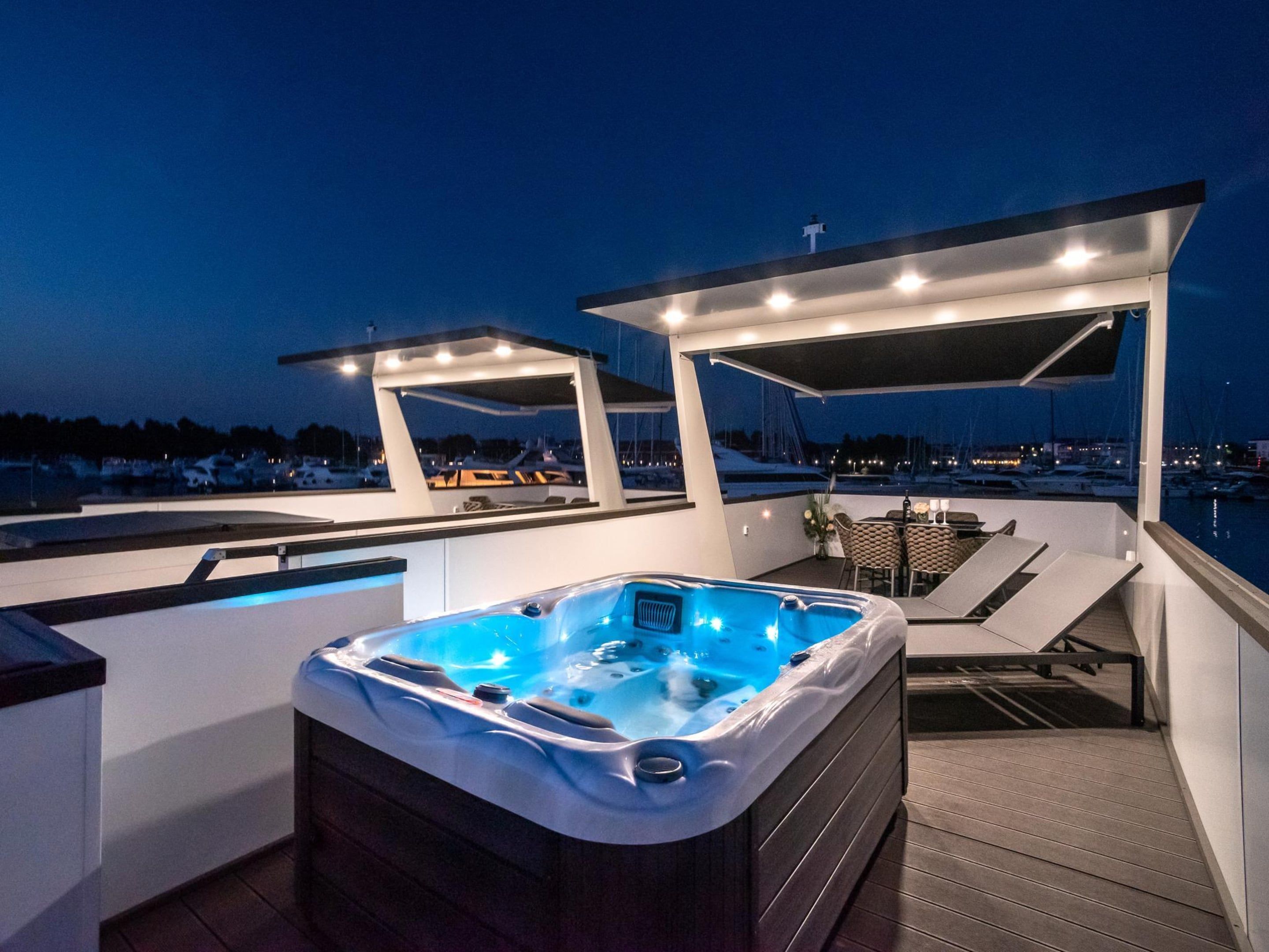 A hot tub on a deck with a view of the marina at dusk.