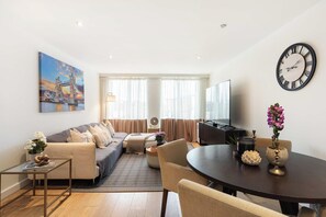 Ein modernes Wohnzimmer mit einer Couch, einem Esstisch und einer großen Uhr an der Wand.